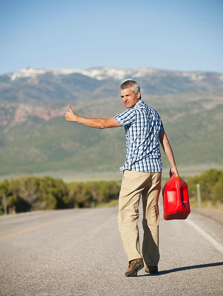 USA, Utah, Kanosh, Mid adult man carrying empty canister attempting to stop vehicles for help