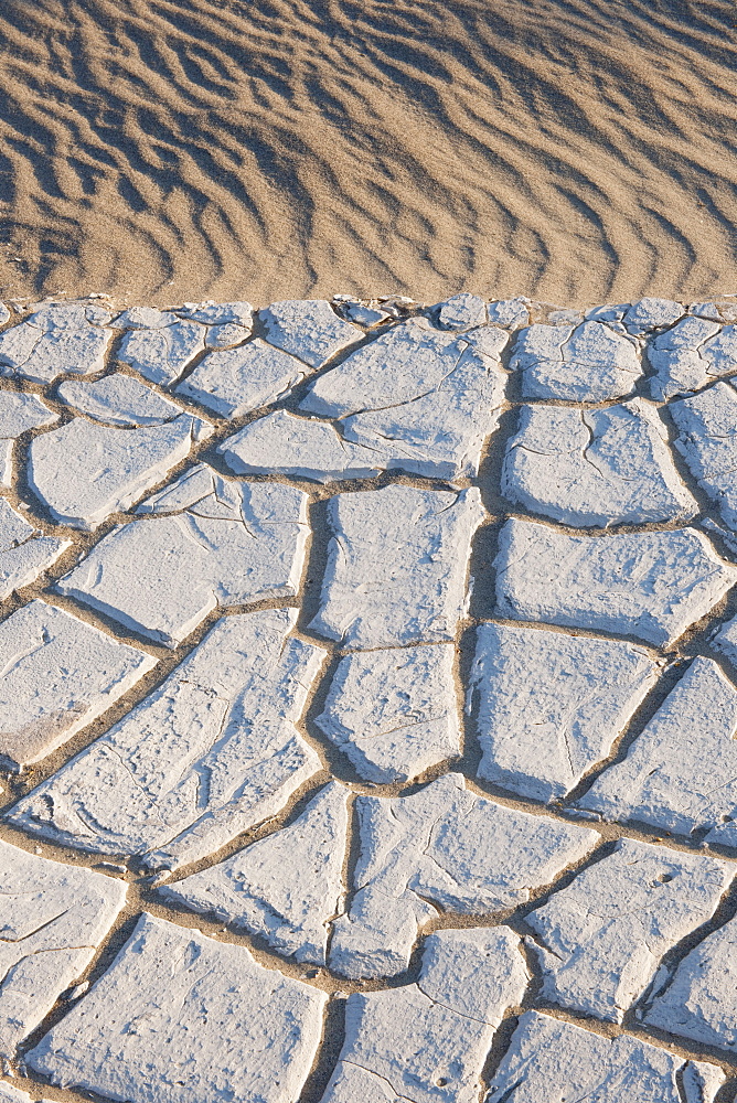 Sand dunes in the desert with cracked earth