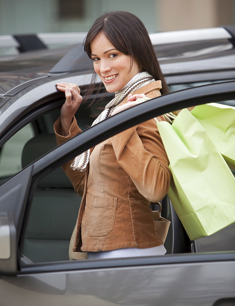 Portrait of woman getting into car with shopping bags