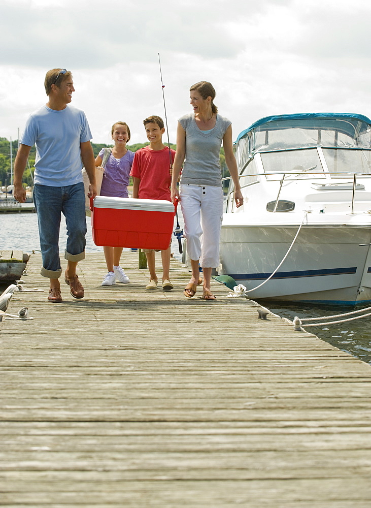 Family walking on boat dock with cooler