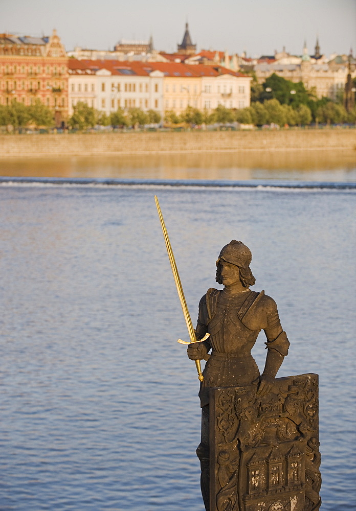 Statue in front of river and city