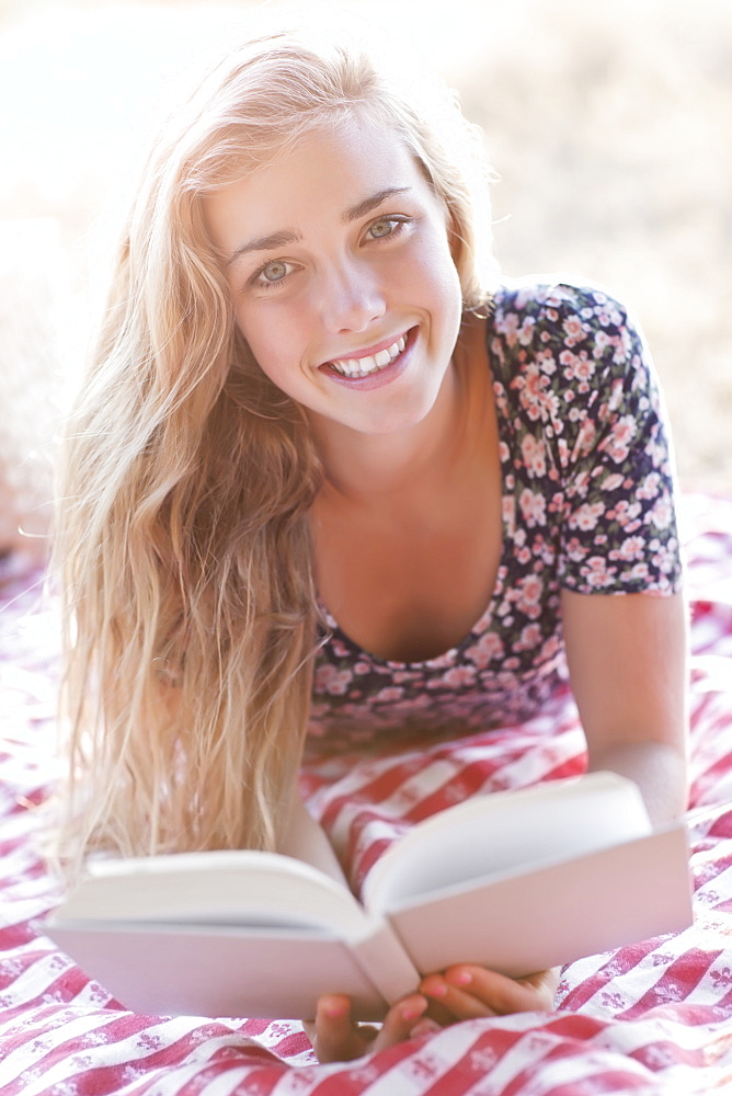 Happy teenage girl (16-17) reading book outdoors