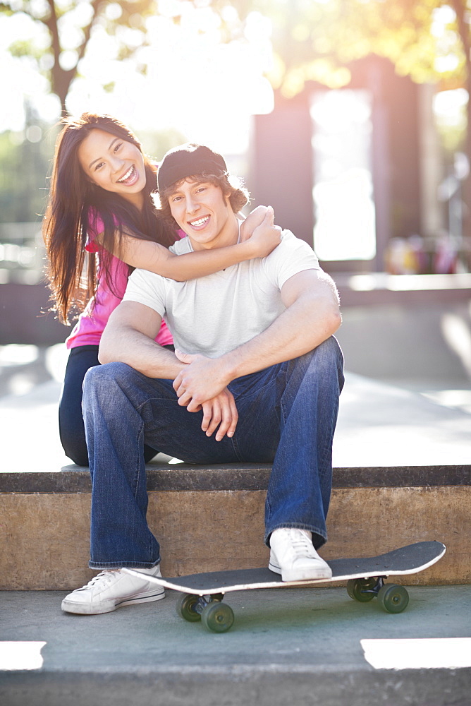 Young multi-racial couple posing with skateboard