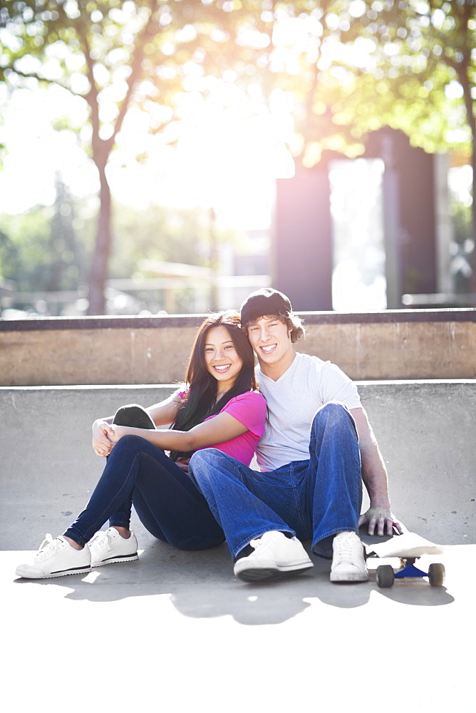 Young multi-racial couple posing with skateboard
