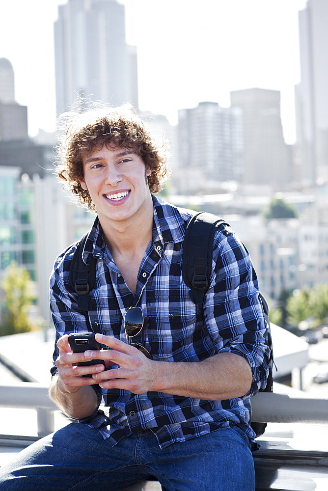 USA, Washington, Seattle, Man text messaging outdoors, skyline in background