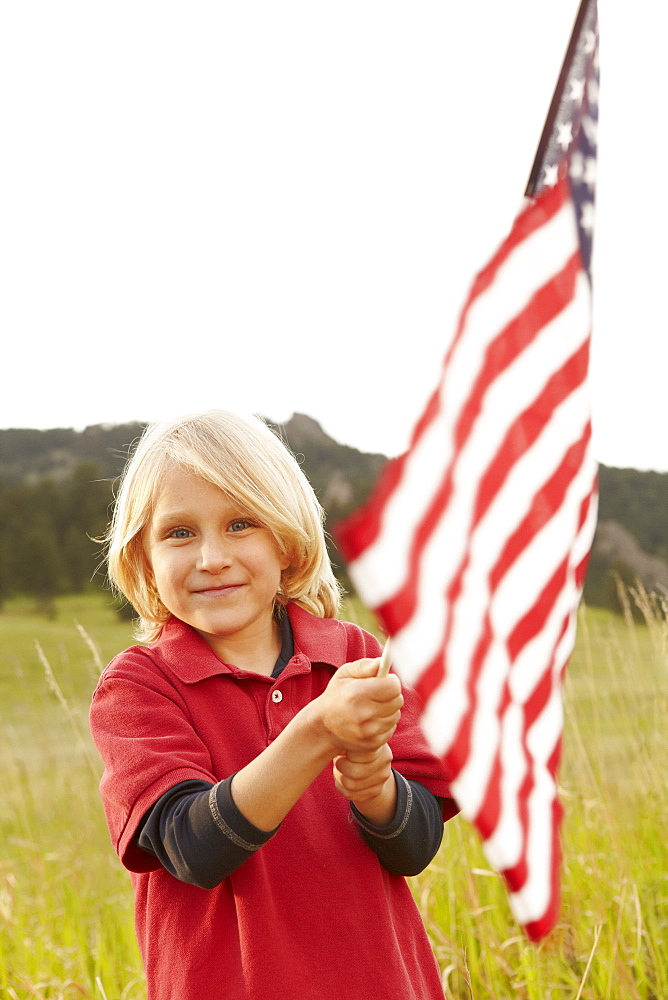 Portrait of boy (6-7) waving American flag