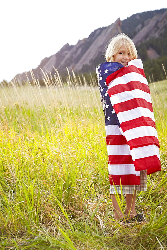 Portrait of boy (6-7) wrapped in American flag