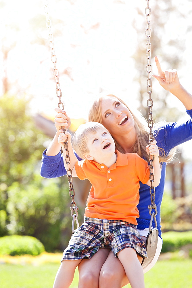 USA, Washington State, Seattle, Mother and son (2-3) swinging on swing in park