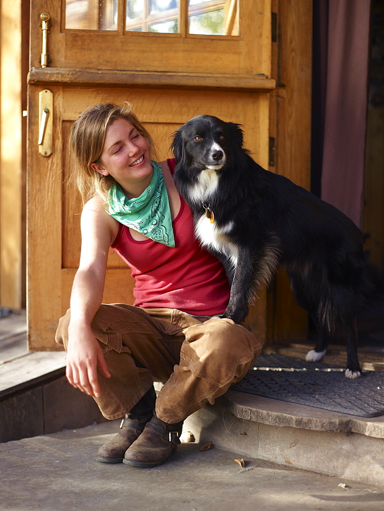 Young woman with dog sitting on porch