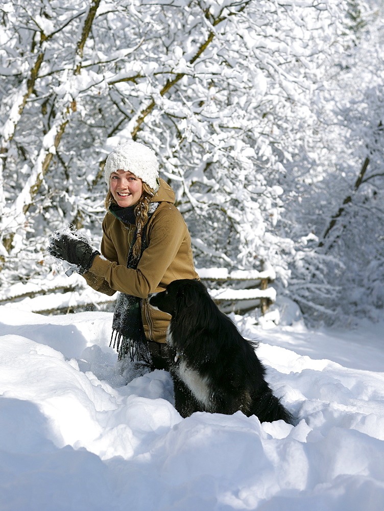 USA, Colorado, young woman playing with dog in snow