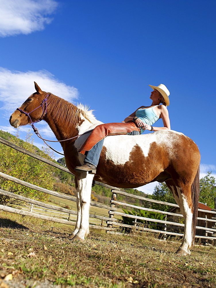 USA, Colorado, Cowgirl relaxing with horse on ranch