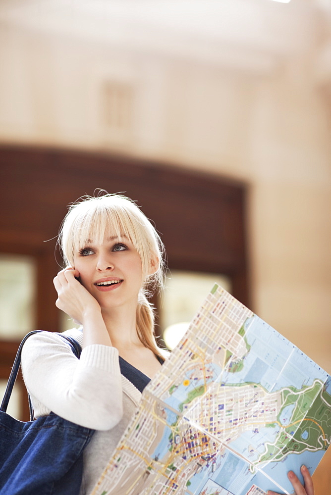 USA, Seattle, Young woman talking via phone and holding map