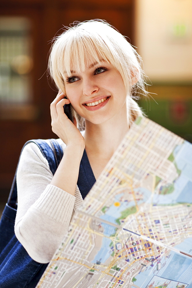 USA, Seattle, Young woman talking via phone and holding map