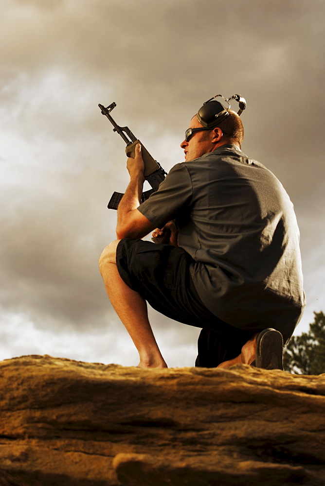 Man holding gun on rocks