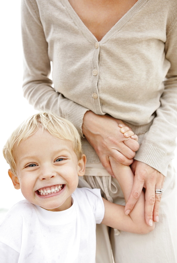 Portrait of boy (4-5) holding mother hand and making face