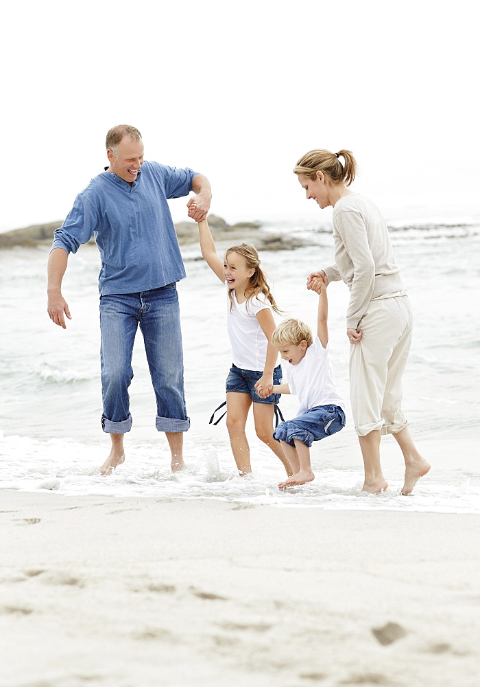 Girl (10-11) and boy (4-5) playing on beach with parents