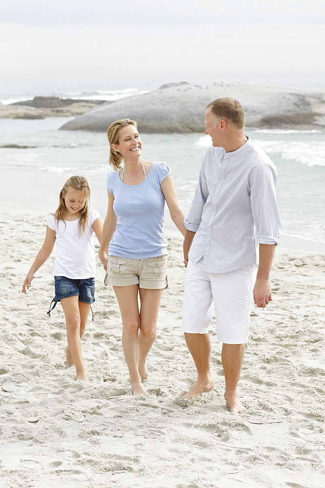 Girl (10-11) playing on beach with parents