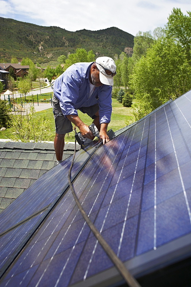 Construction worker installing solar panel on roof