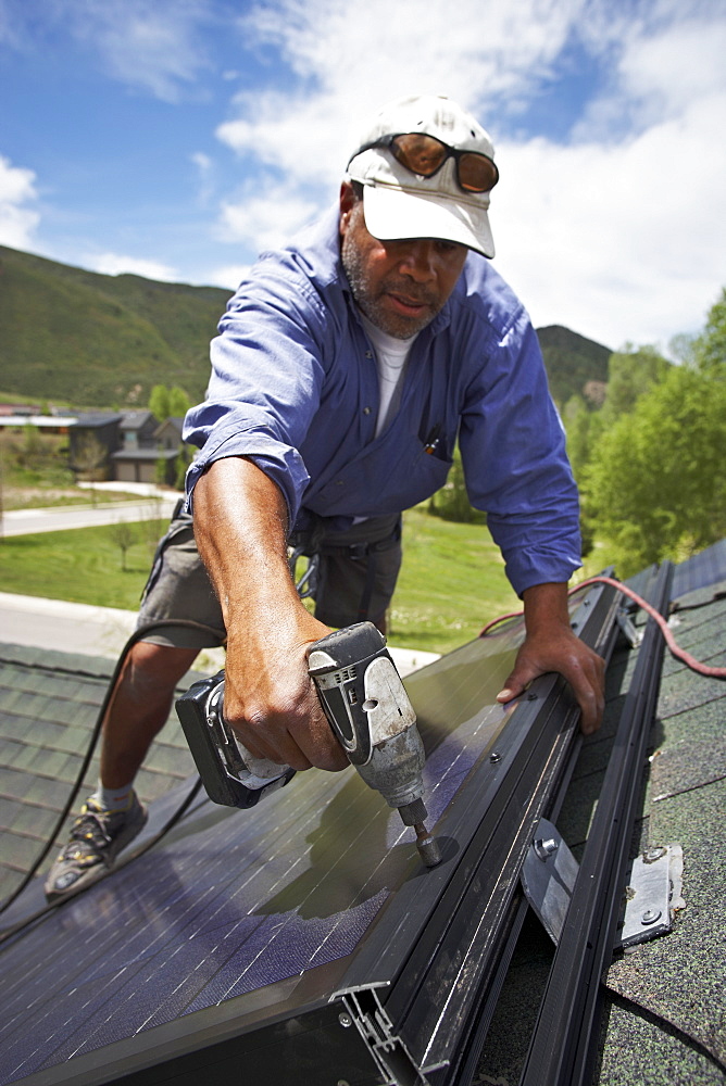 Construction worker installing solar panel on roof