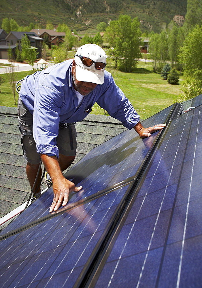 Construction worker installing solar panel on roof