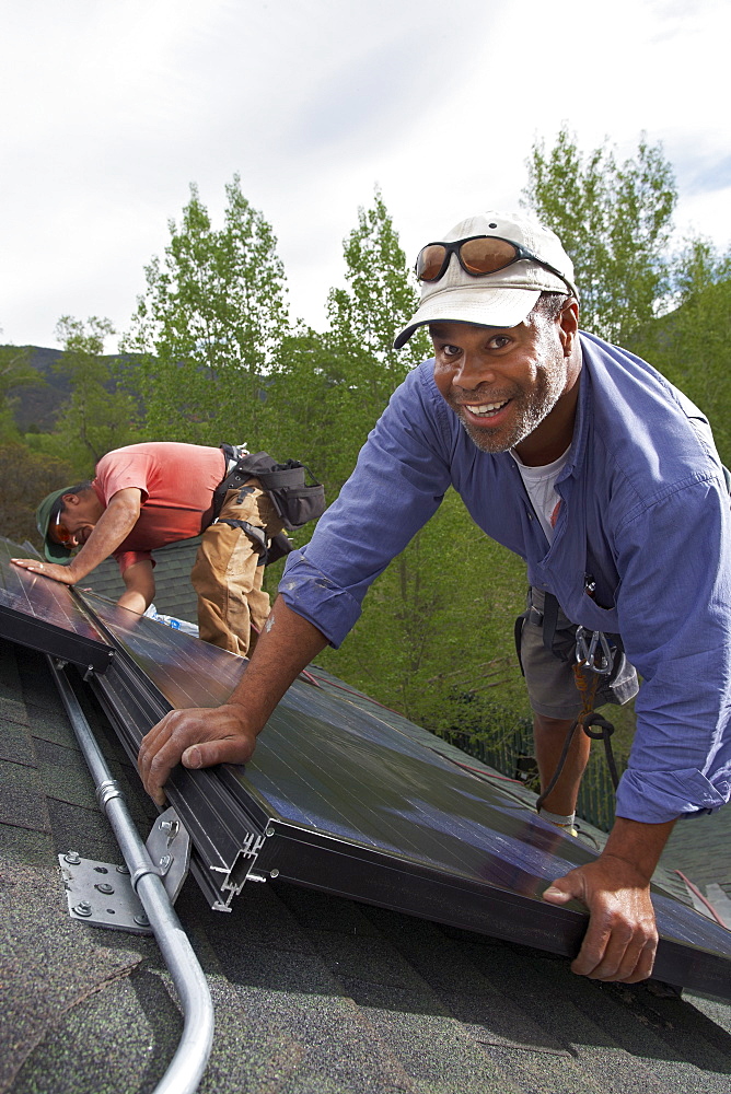 Construction workers installing solar panels on roof