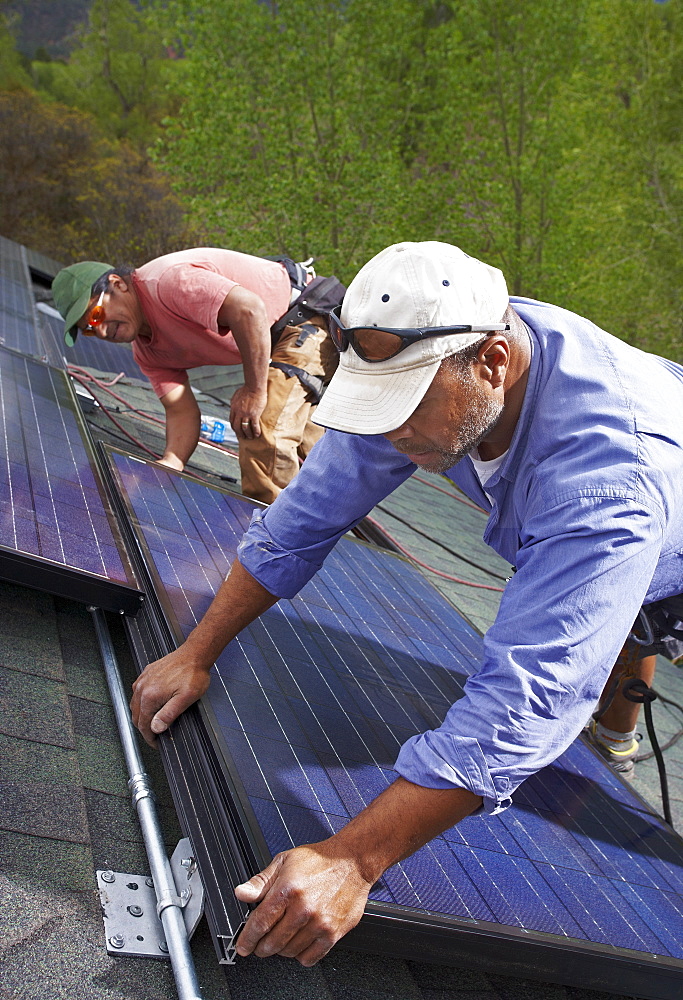 Construction workers installing solar panels on roof