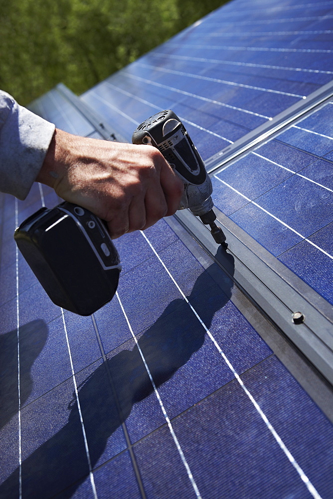 Construction worker installing solar panel on roof