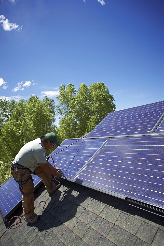 Construction worker installing solar panel on roof