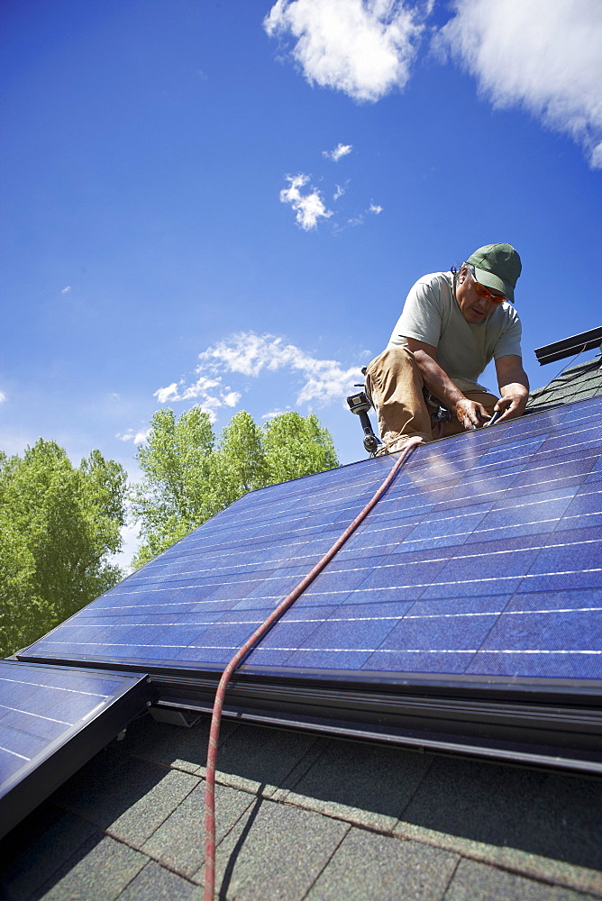 Construction worker installing solar panel on roof