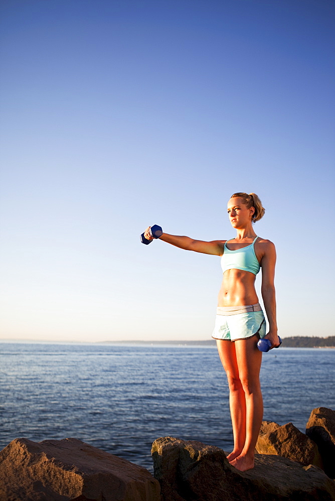 Athletic woman lifting weights outdoors