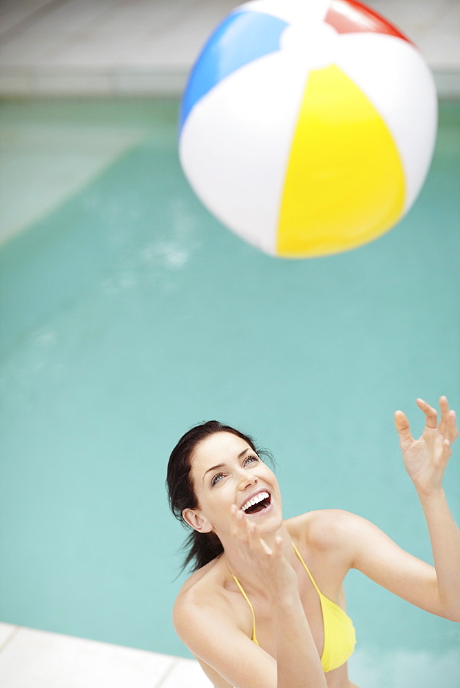 Attractive brunette playing with a beach ball