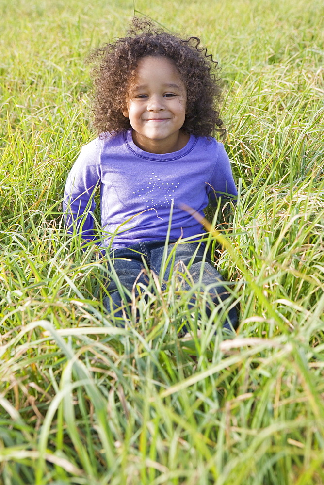 Young girl sitting in tall grass