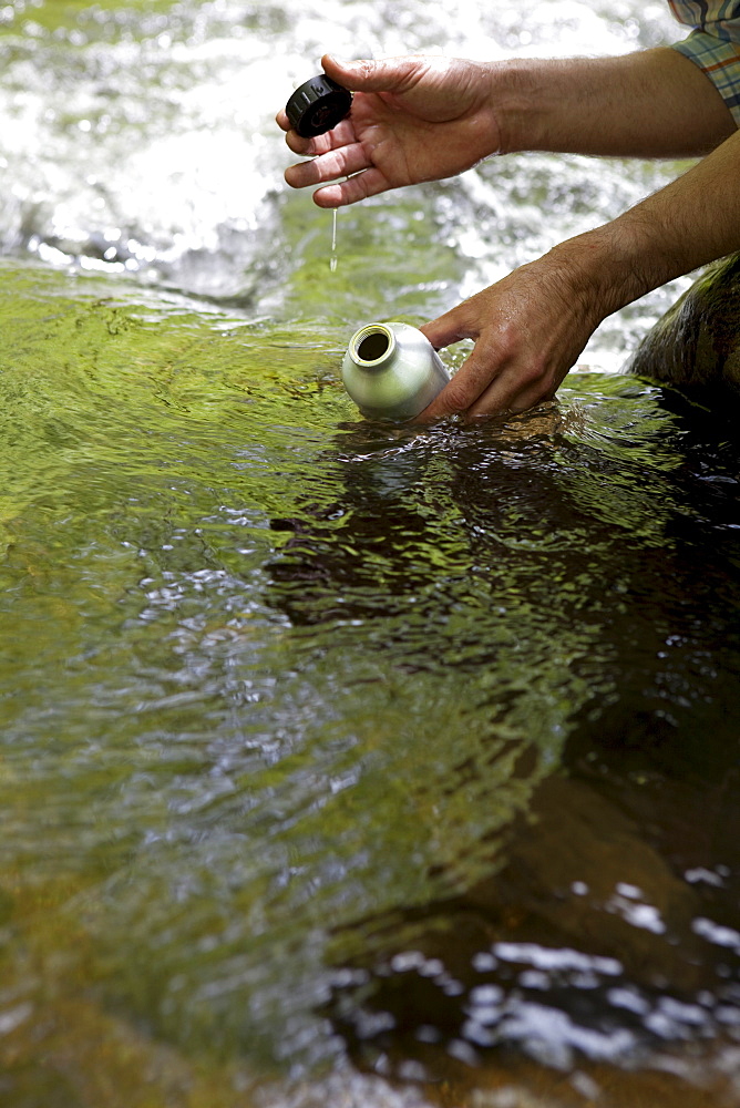 A man with a reusable water bottle in the woods