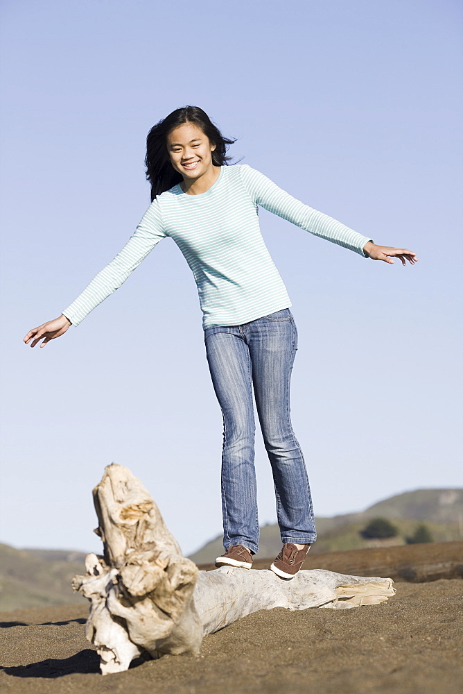 Teenage girl balancing on driftwood