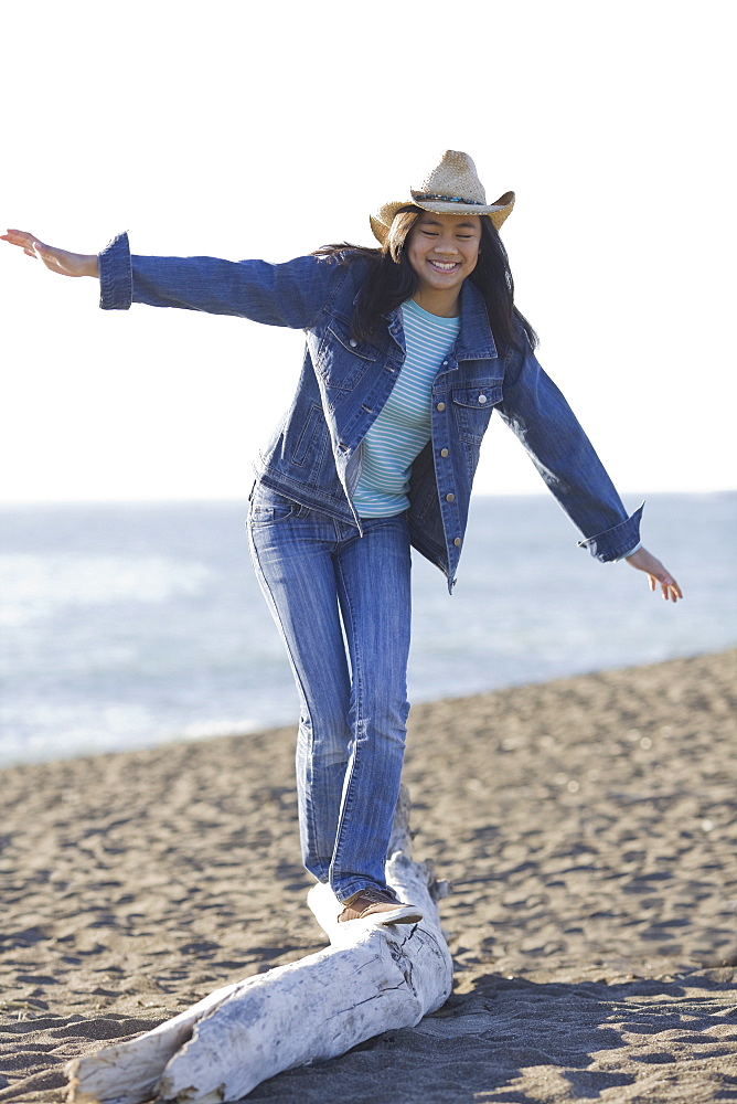 Teenage girl balancing on driftwood