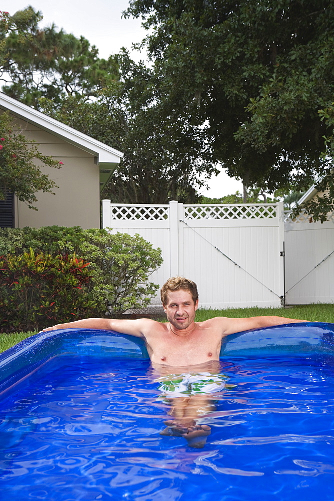 Portrait of man soaking in inflatable swimming pool