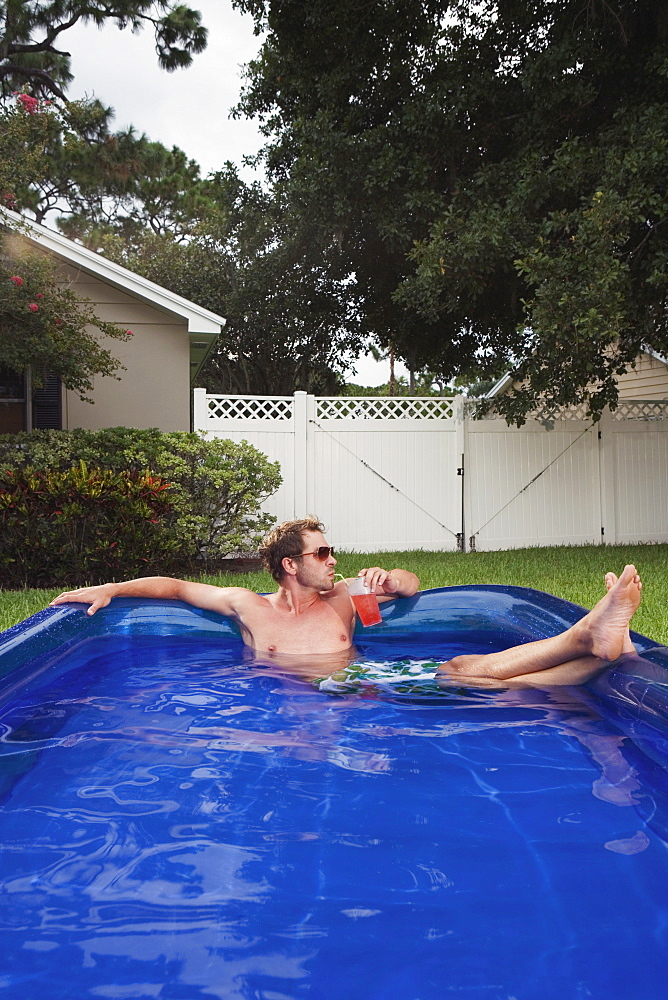 Man relaxing in inflatable swimming pool