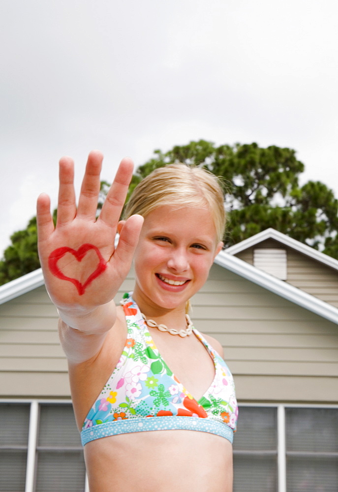 Girl holding out hand painted with heart design