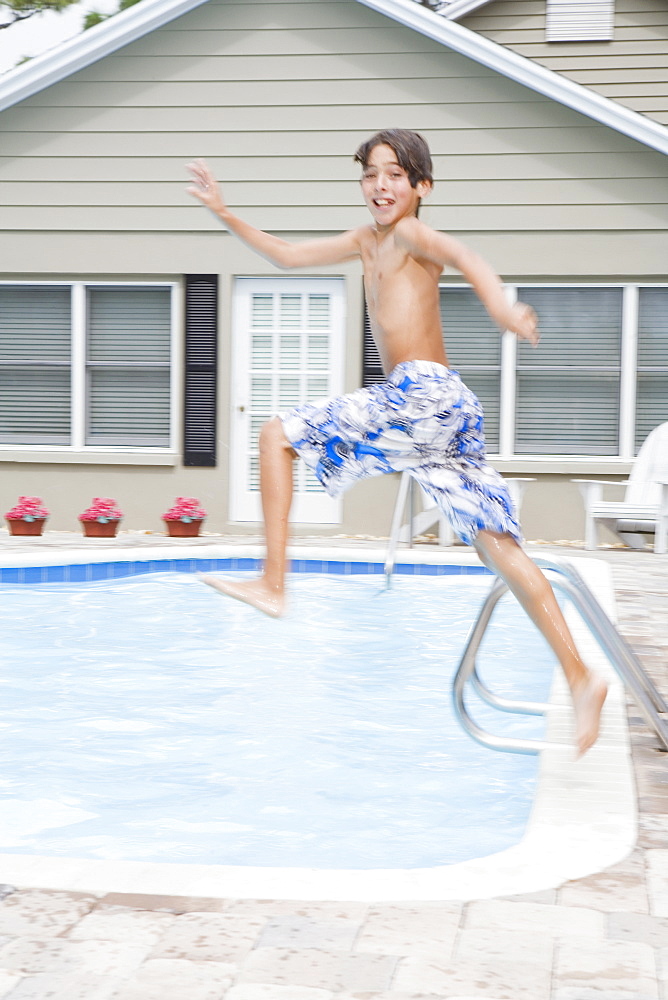 Boy jumping into swimming pool