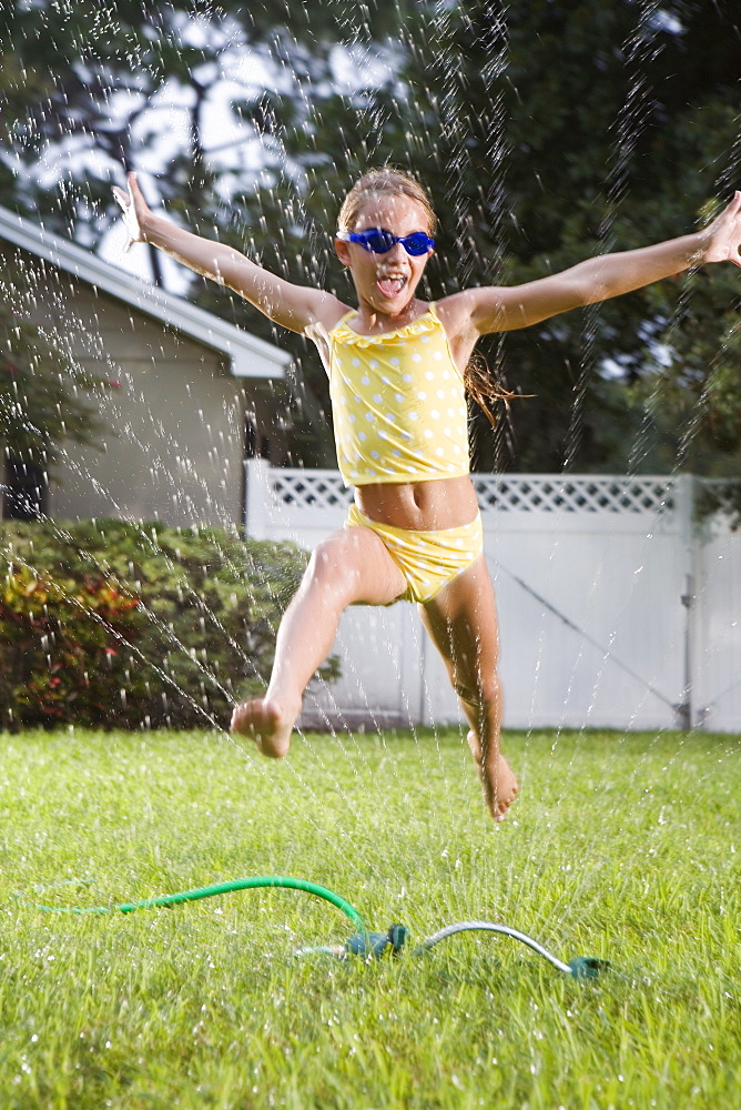 Girl running through sprinkler