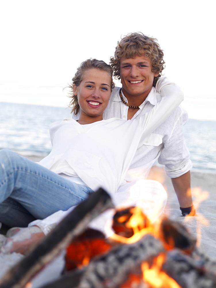 Young couple hugging by campfire on beach