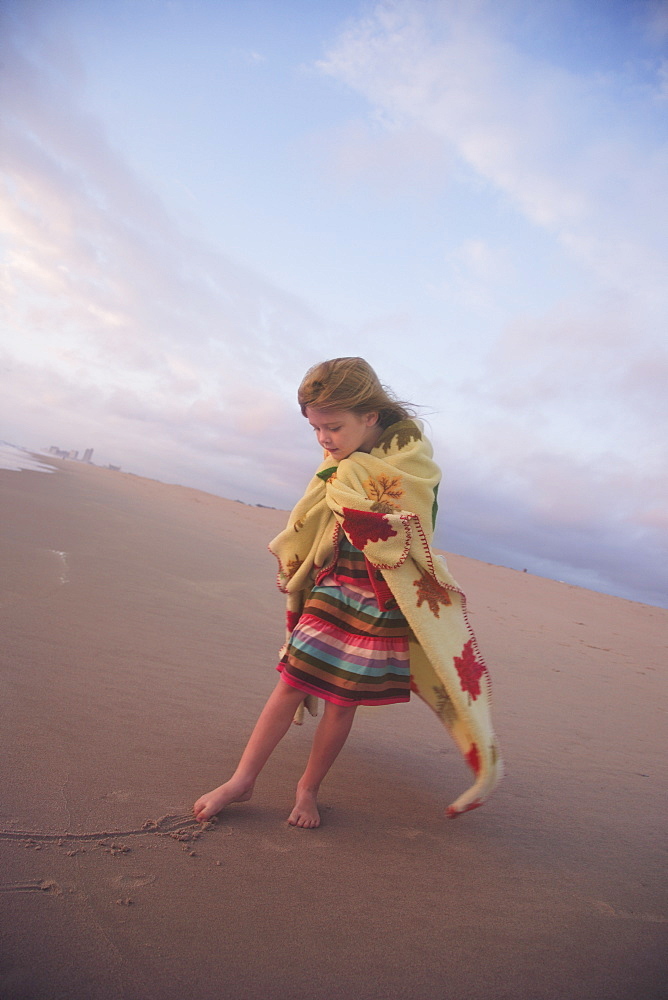 Girl drawing in sand with toe