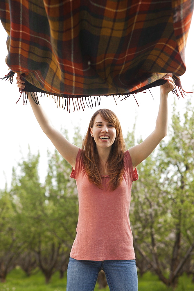 Young woman holding blanket in orchard