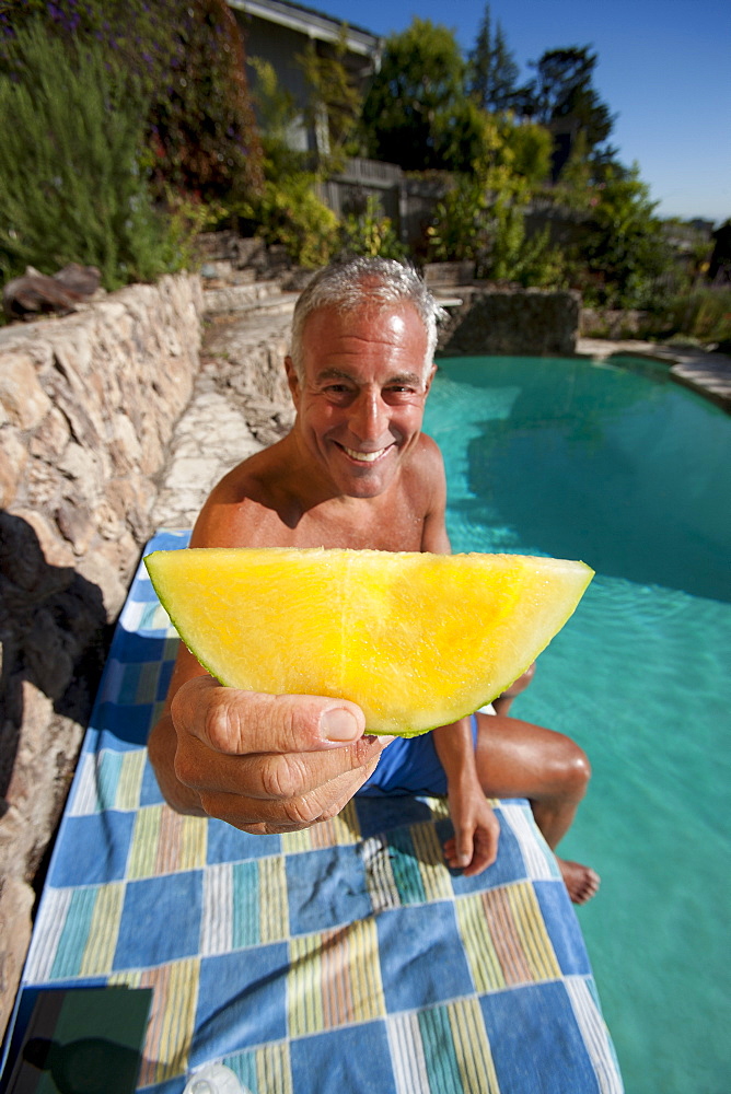 USA, California, Oakland, Senior man relaxing at swimming pool