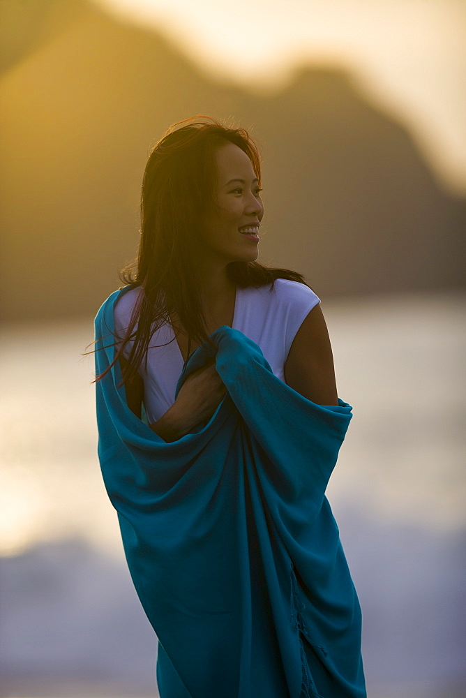 USA, California, San Francisco, Young woman wrapped in blanket at coast