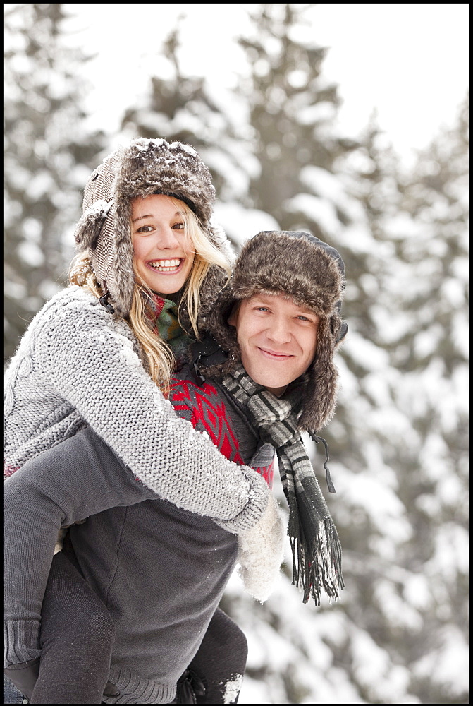 USA, Utah, Salt Lake City, man giving young woman piggy back ride in snow