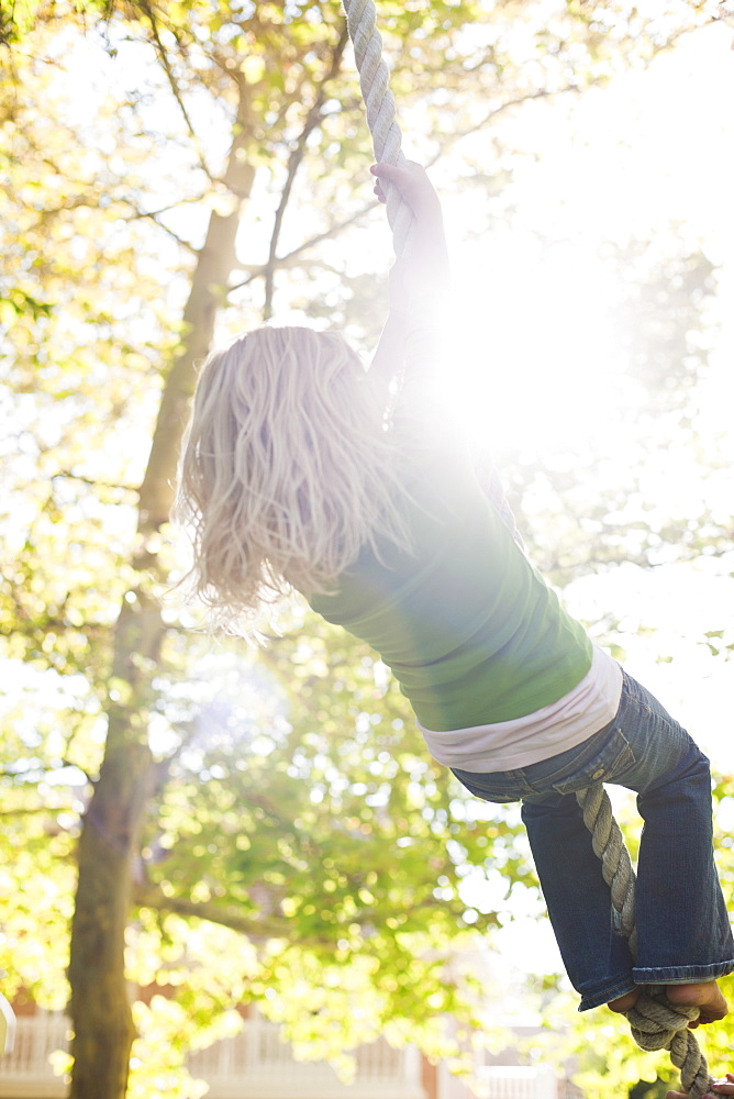 USA, Utah, rear view of girl (8-9) hanging on rope