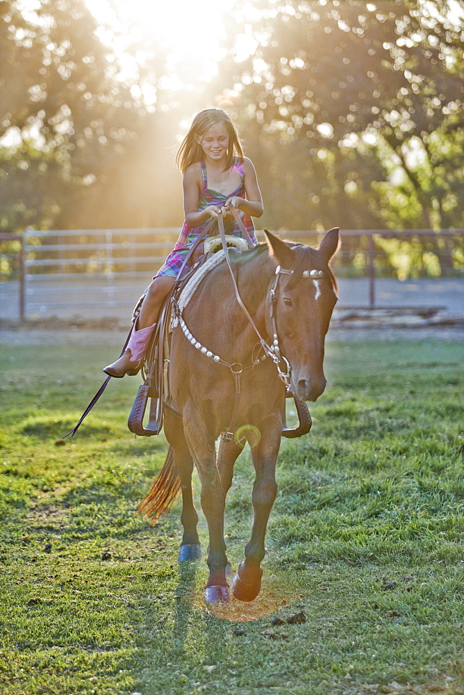 Girl (8-9) riding horse in paddock