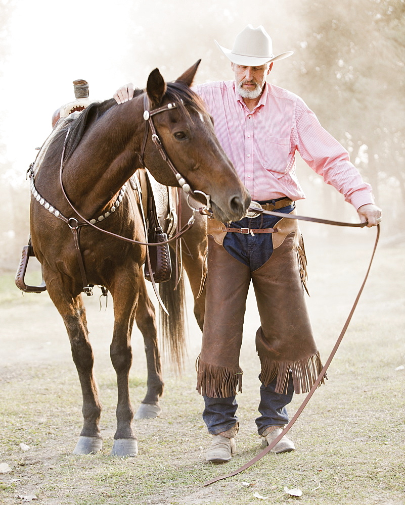 Portrait of senior man with horse in ranch