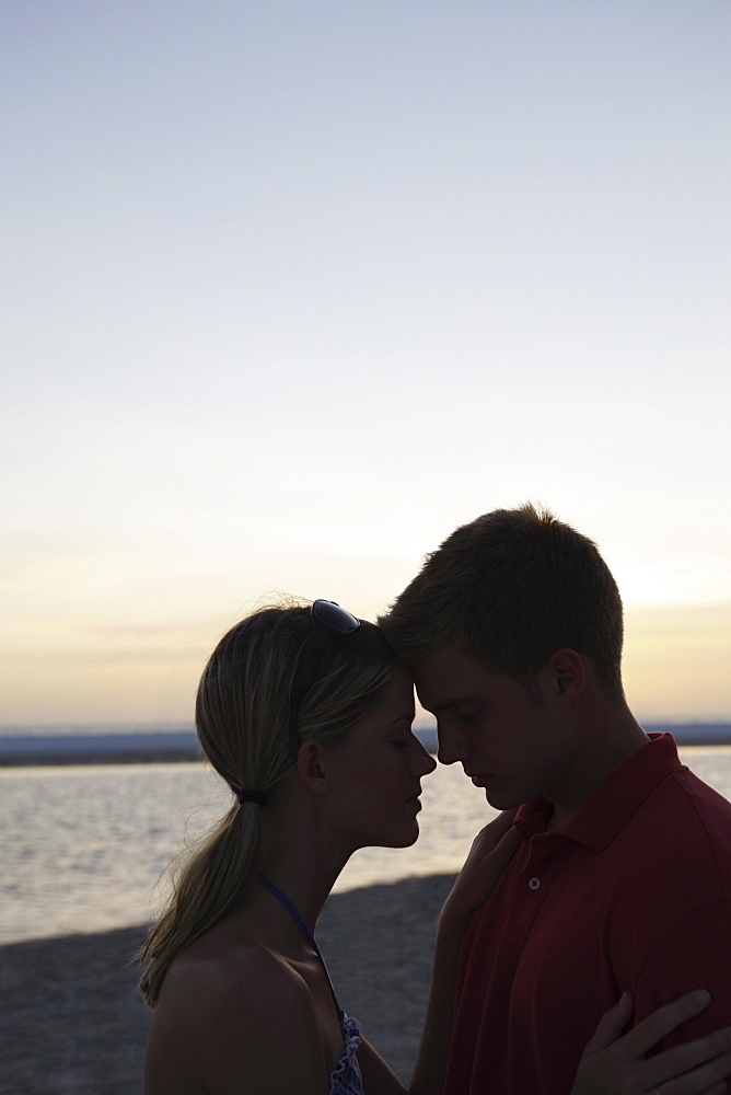 Young couple hugging on beach at sunset